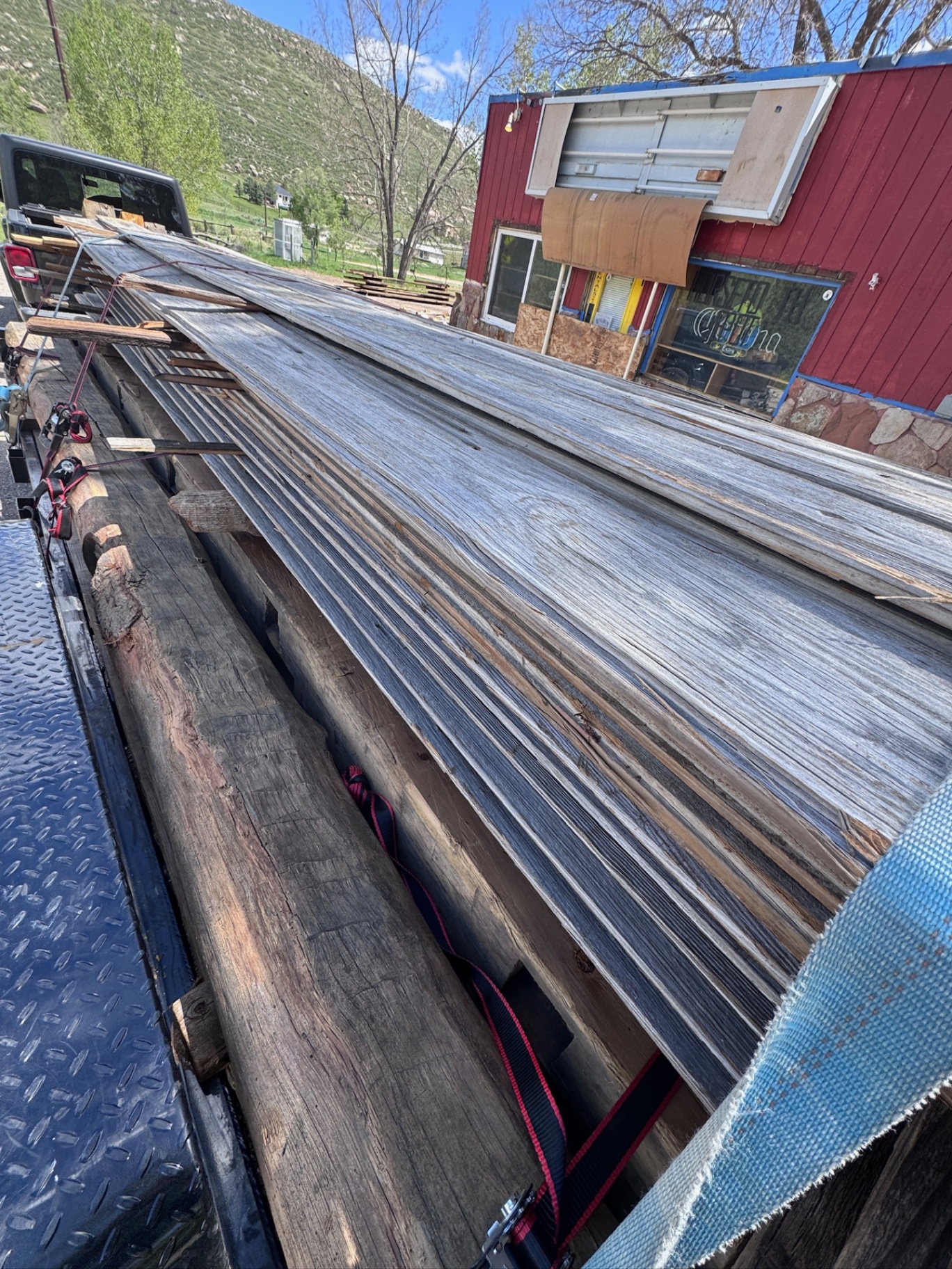 Long load of weathered siding strapped to flatbed