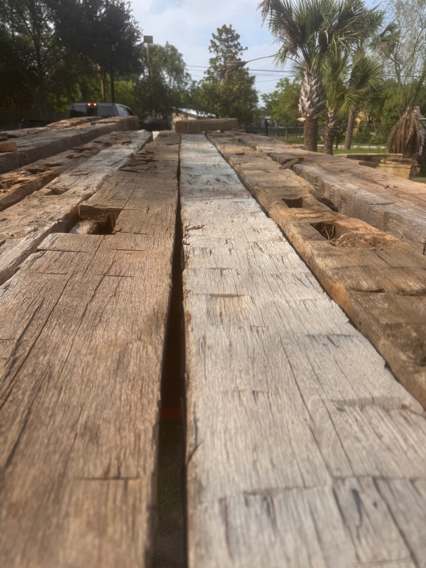 Row of hand hewn barn beams laid out in the yard with mortise pockets