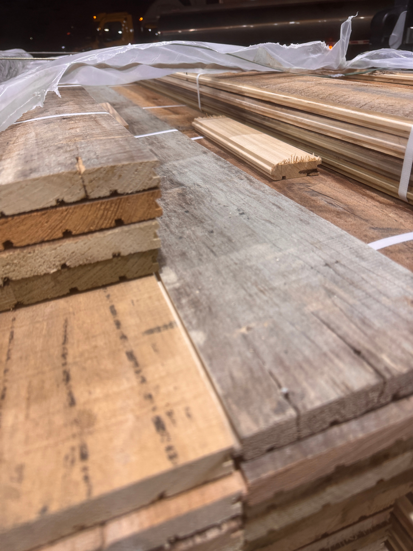 Low-angle view across stacked milled reclaimed boards with finished profiles