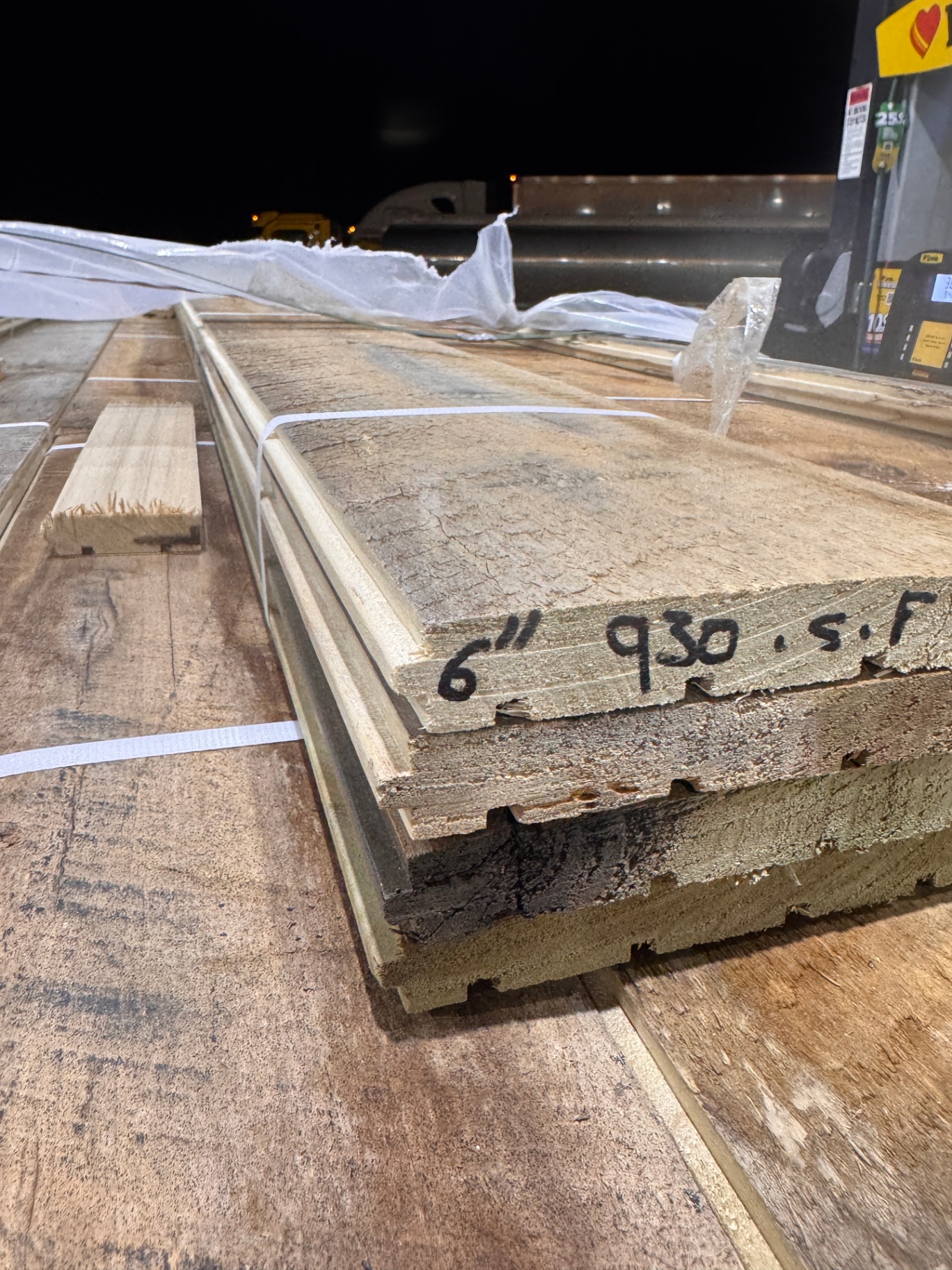 Close view of milled reclaimed boards stacked at night showing tongue-and-groove edges