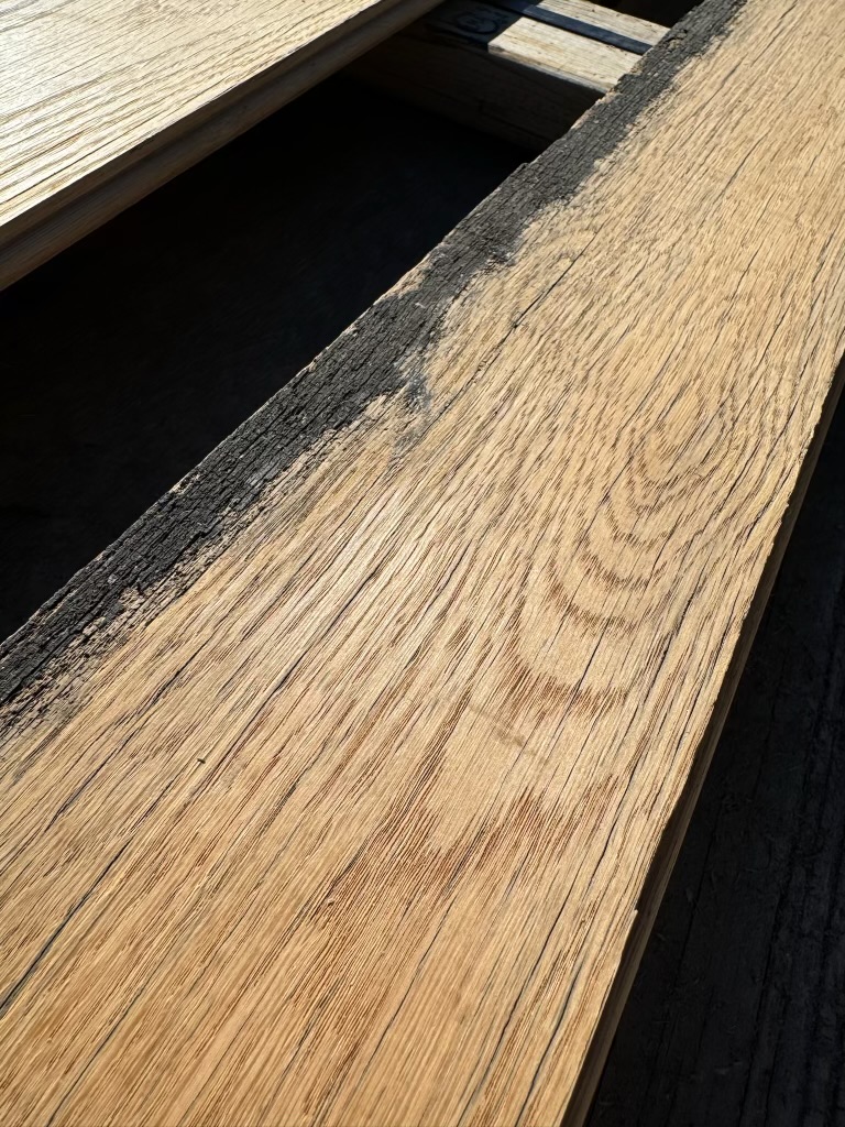 Top face of milled reclaimed plank showing clean grain with preserved dark edge patina