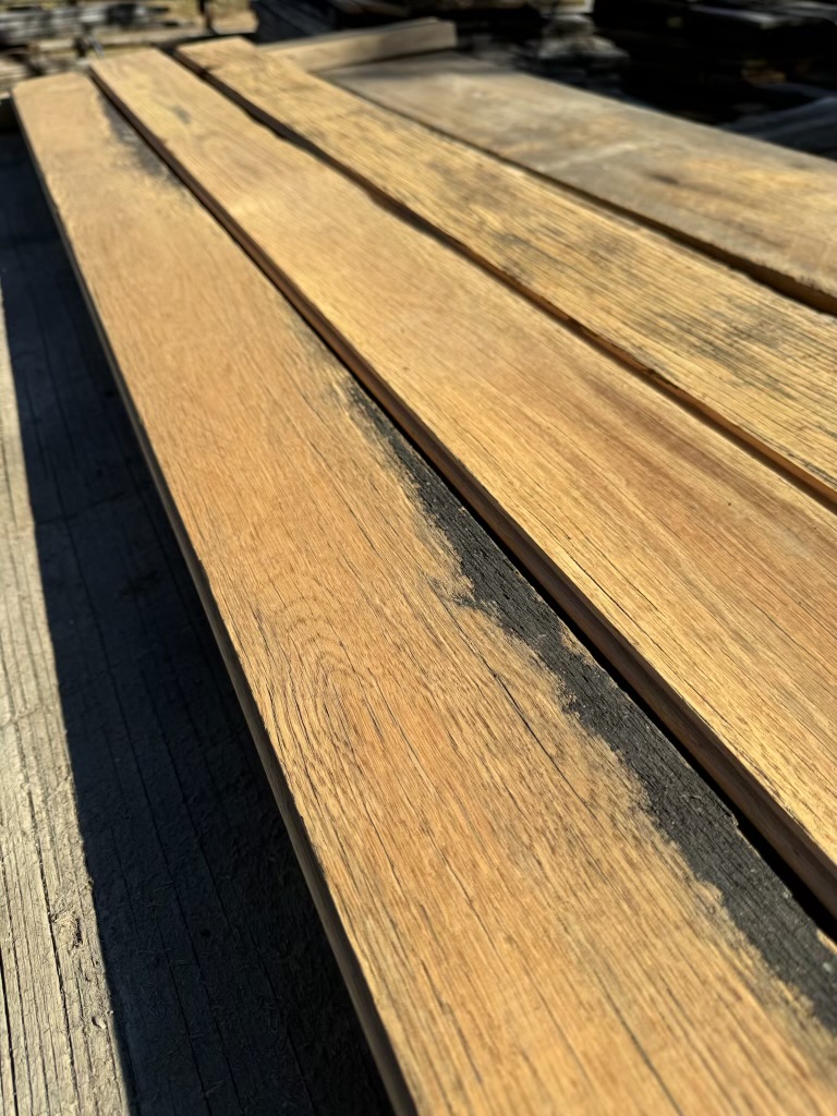 Long run of milled reclaimed planks with warm grain and darker weathered edge detail