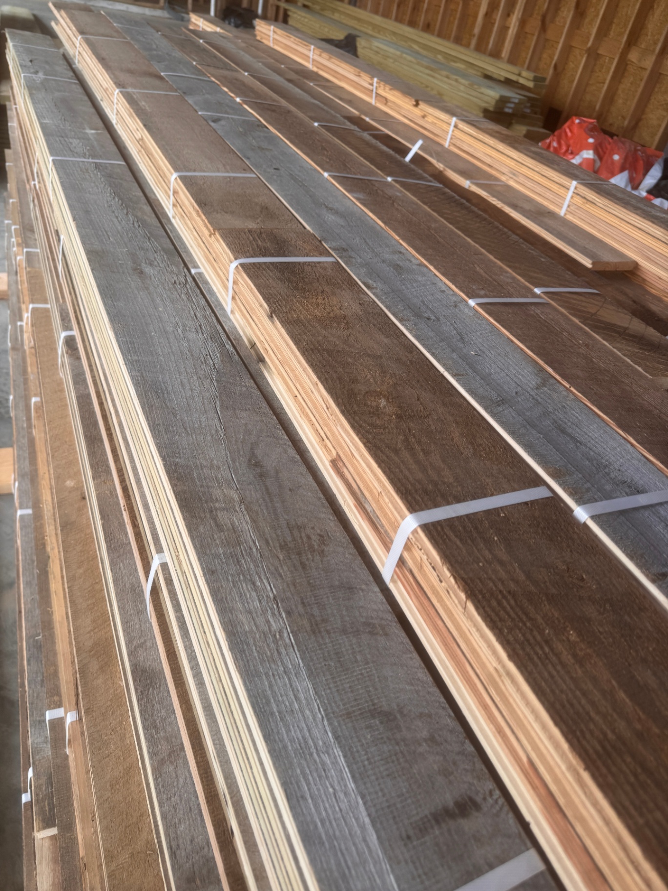 Large indoor stacks of milled reclaimed lumber bundled by length and tone