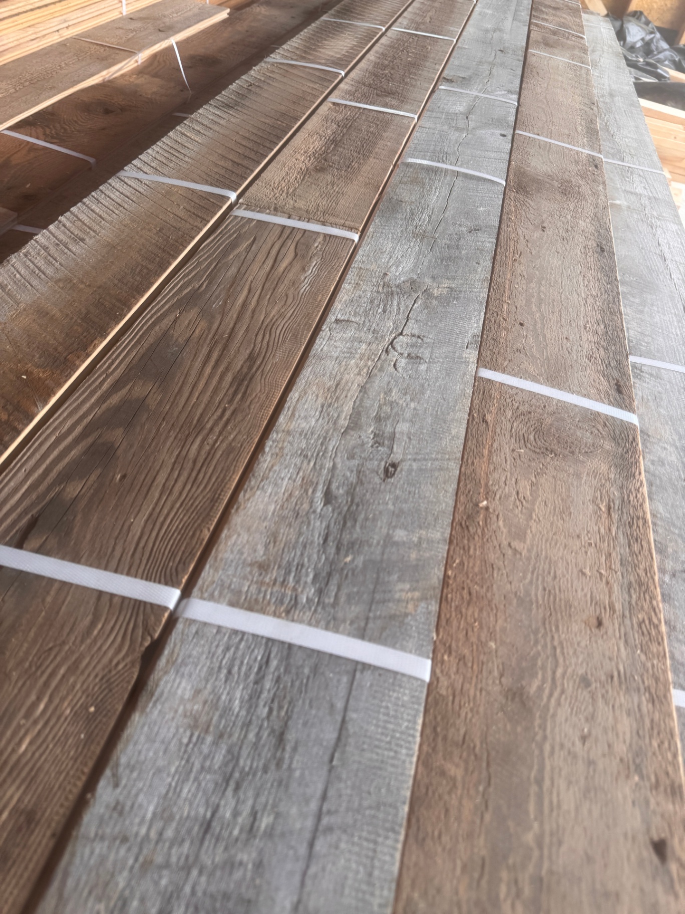 Rows of milled reclaimed boards in varied brown and silver finishes ready for installation