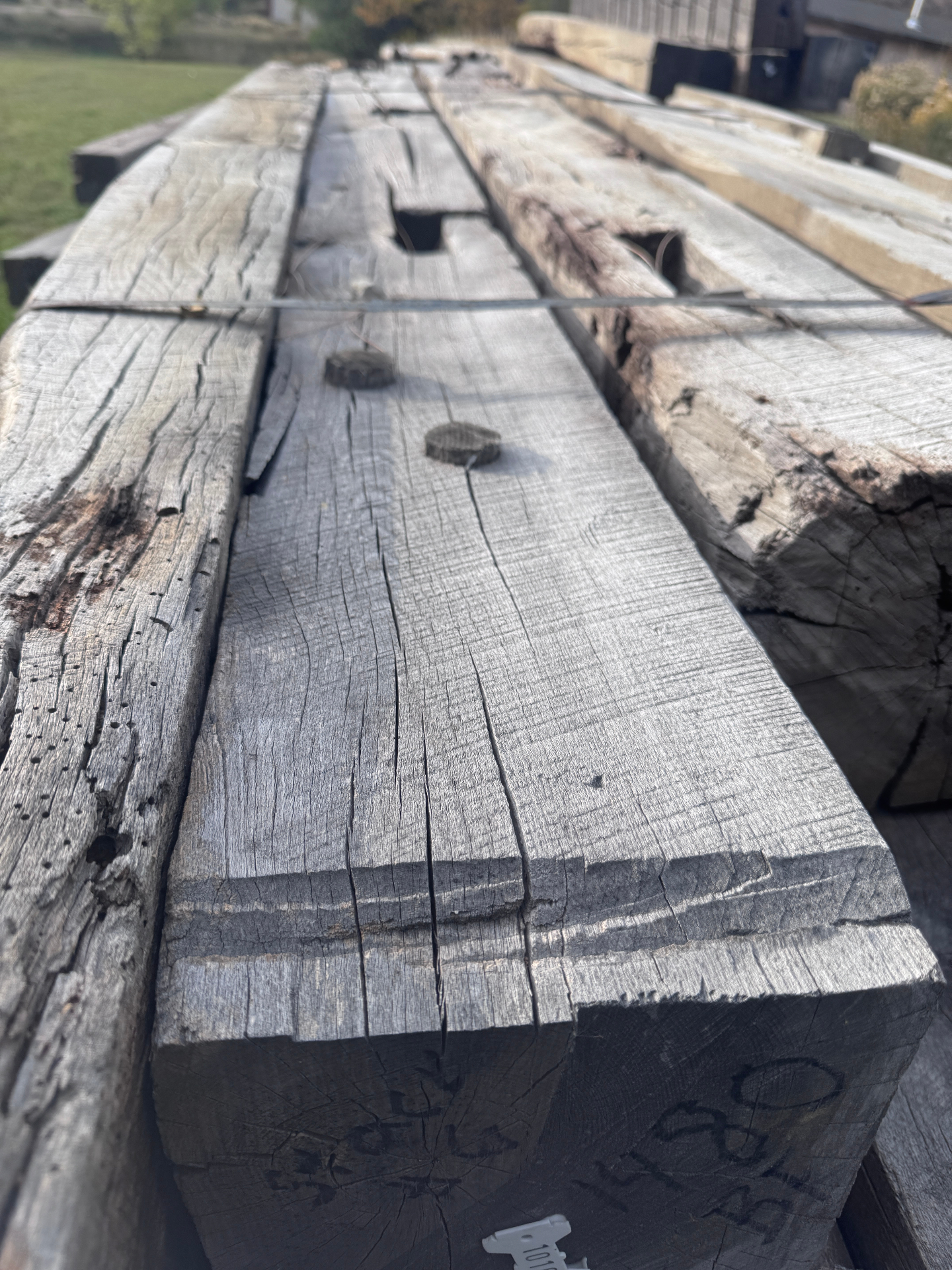 End grain and top faces of rough sawn reclaimed beams showing age checks
