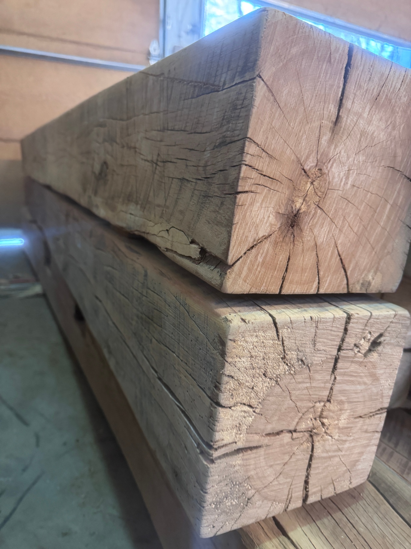 End-grain view of two stacked sanded reclaimed oak beams with warm tones and visible checks