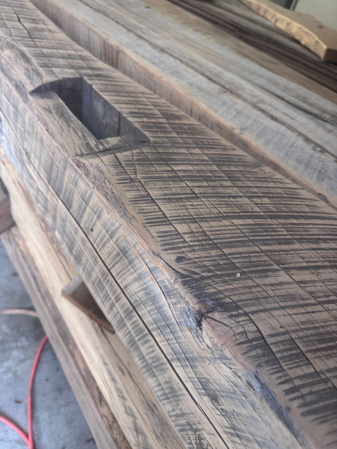 Top face of sanded reclaimed beam with mortise pocket and crosshatched saw texture