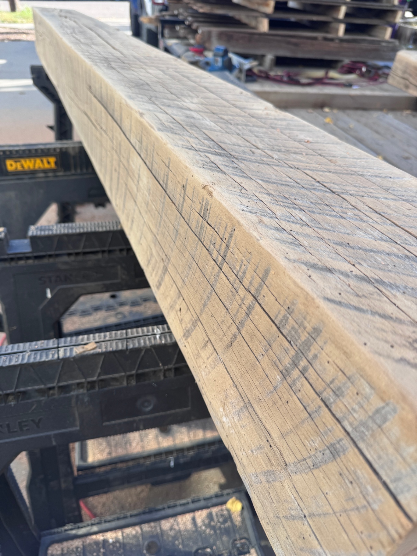 Long sanded reclaimed beam on sawhorses showing clean grain and weathered streaks