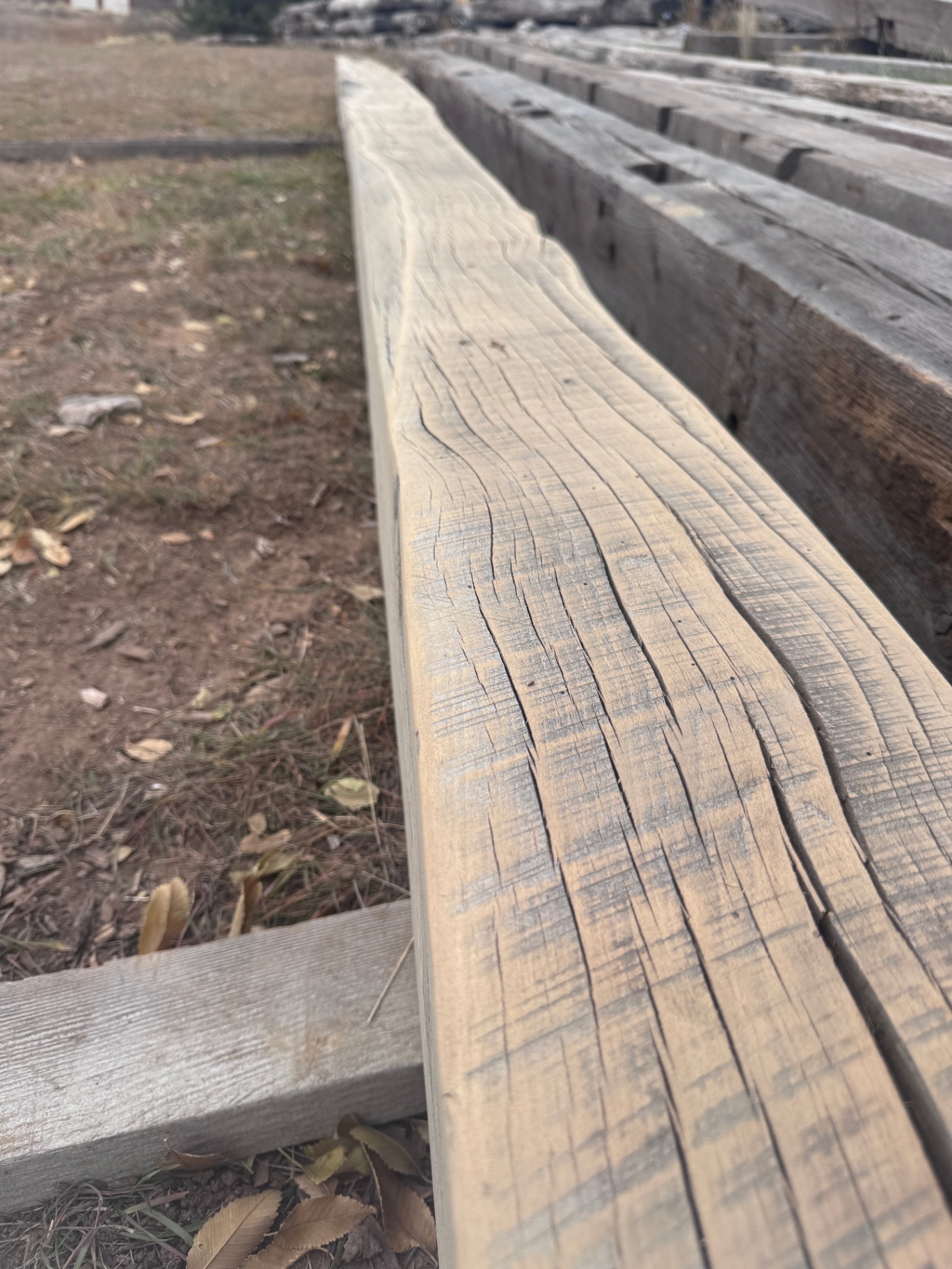 Close low-angle along the edge of a long sanded reclaimed beam in the yard