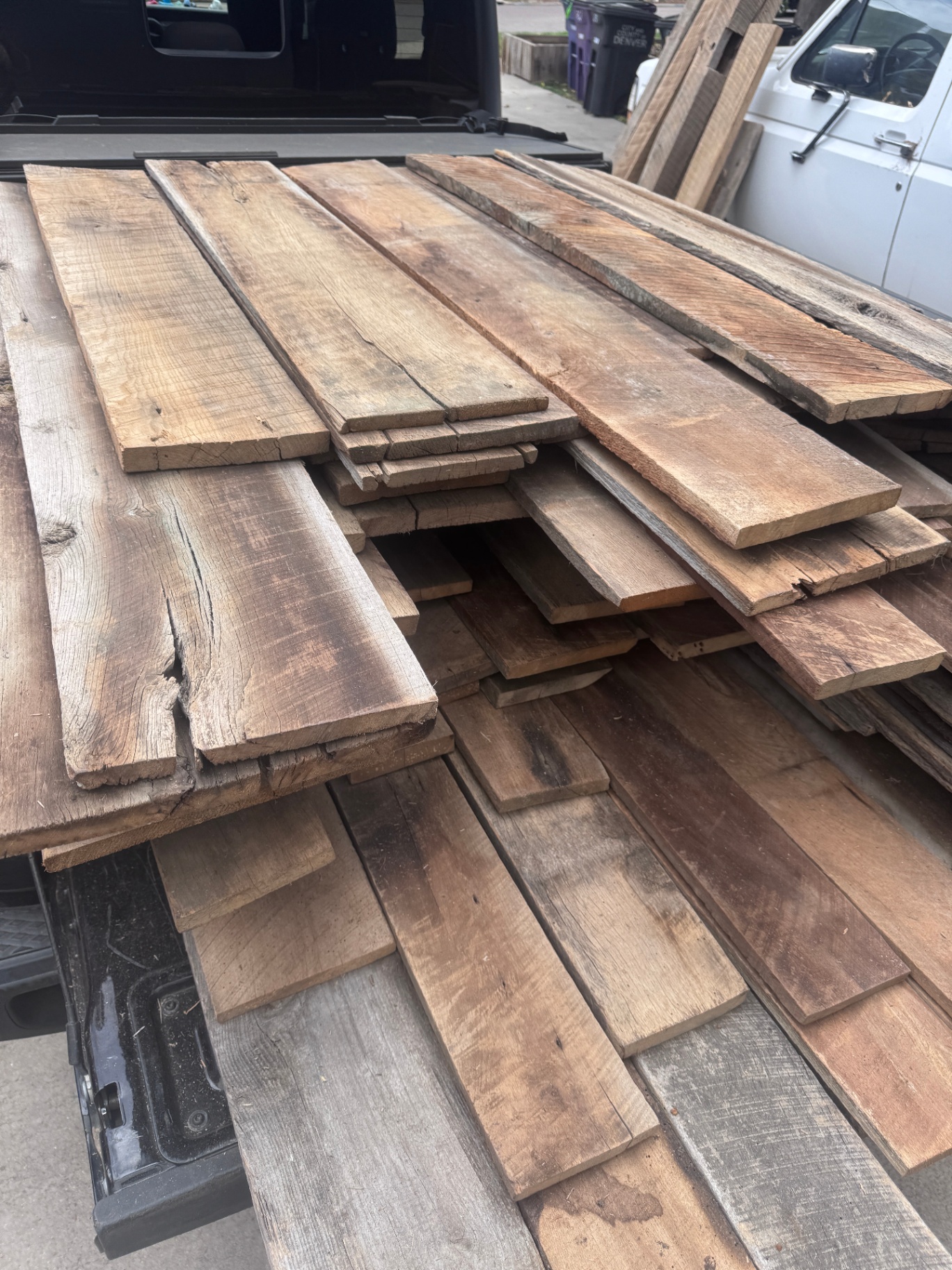 Stacked reclaimed barnwood siding boards in varied widths on truck bed