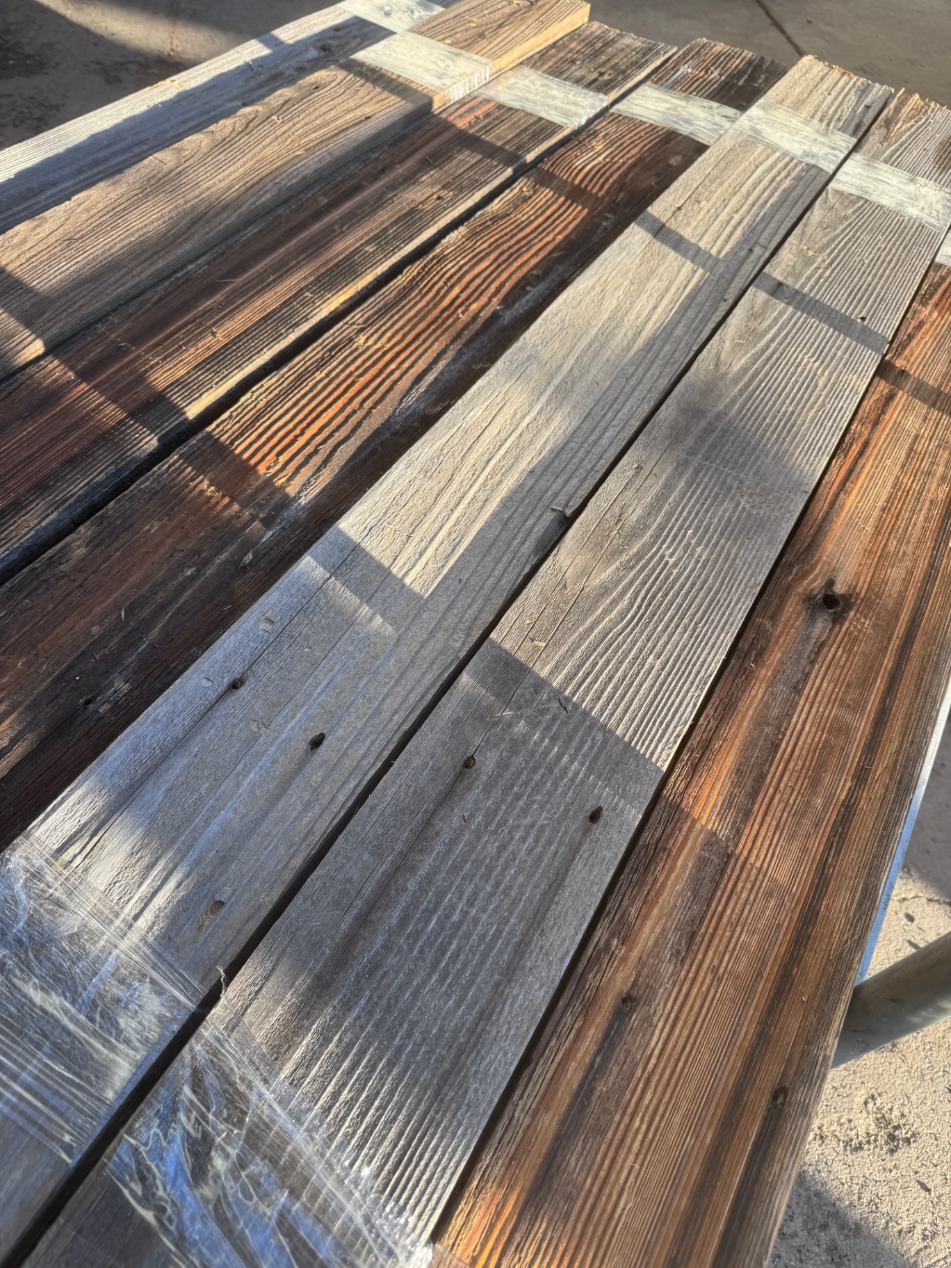 Sun-lit bundle of snow fencing planks with rich brown and grey color variation