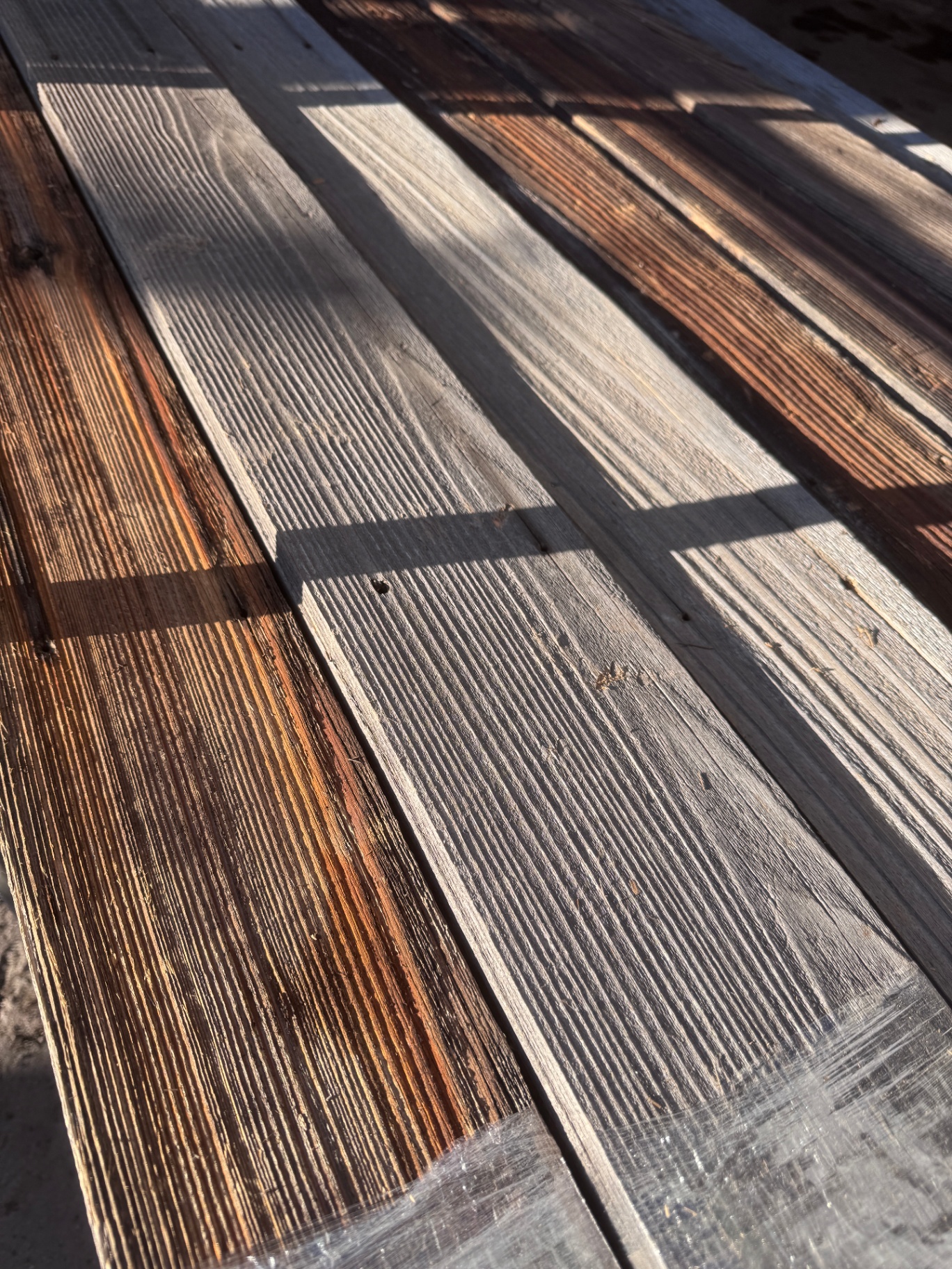 Close-up of snow fence boards in sunlight showing ribbed grain and amber highlights