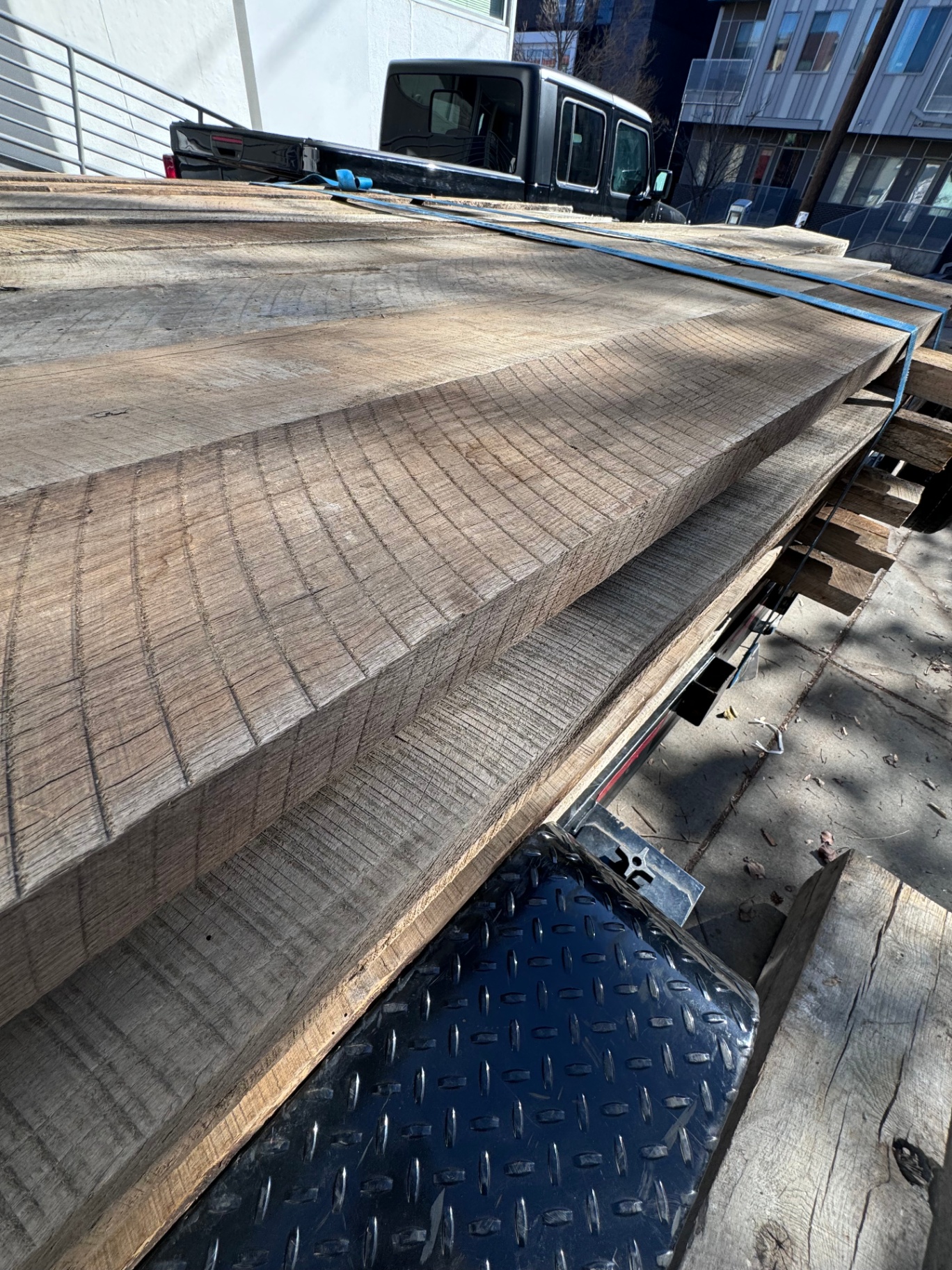 Thick reclaimed 2-inch hardwood planks stacked on trailer showing bold saw marks