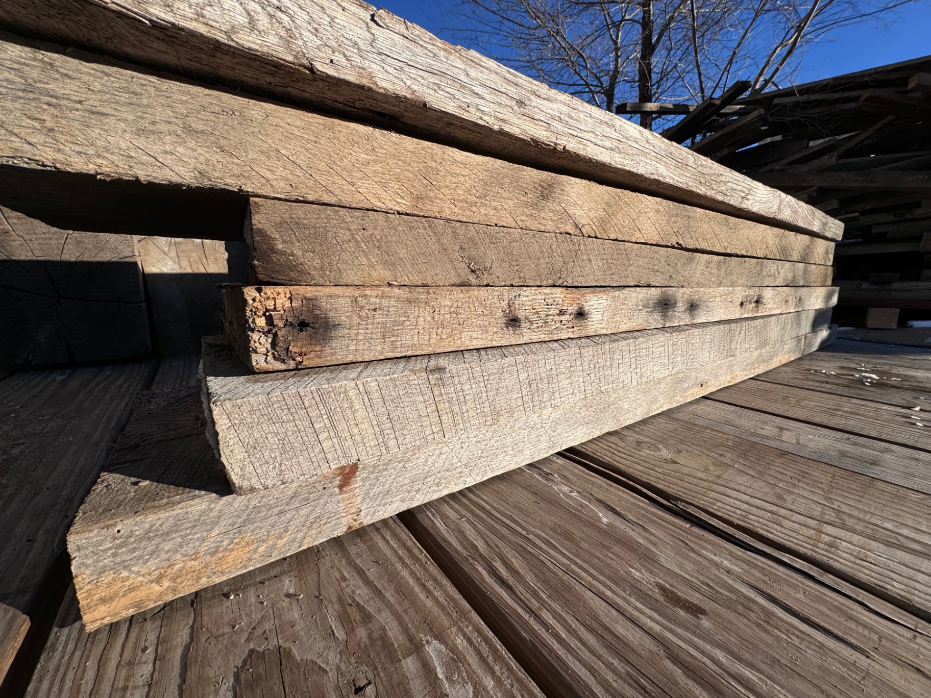 Stacked 2-inch hardwood boards with aged edges and mixed weathered tones